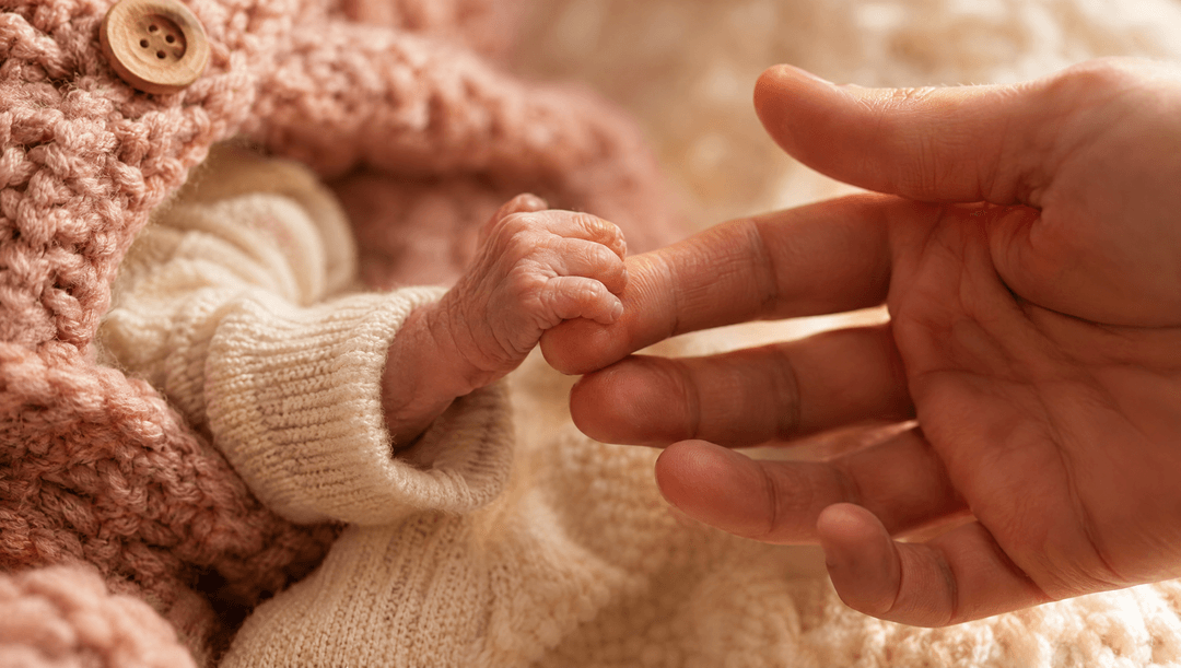 Het handje van een premature baby dat de vinger van een ouder vasthoudt